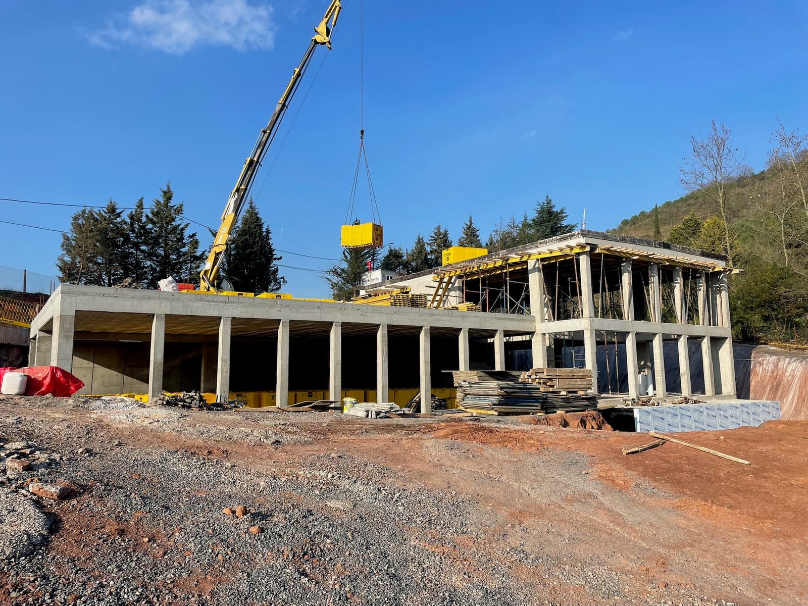 A completed concrete frame of a long low building, with a crane alongside.
