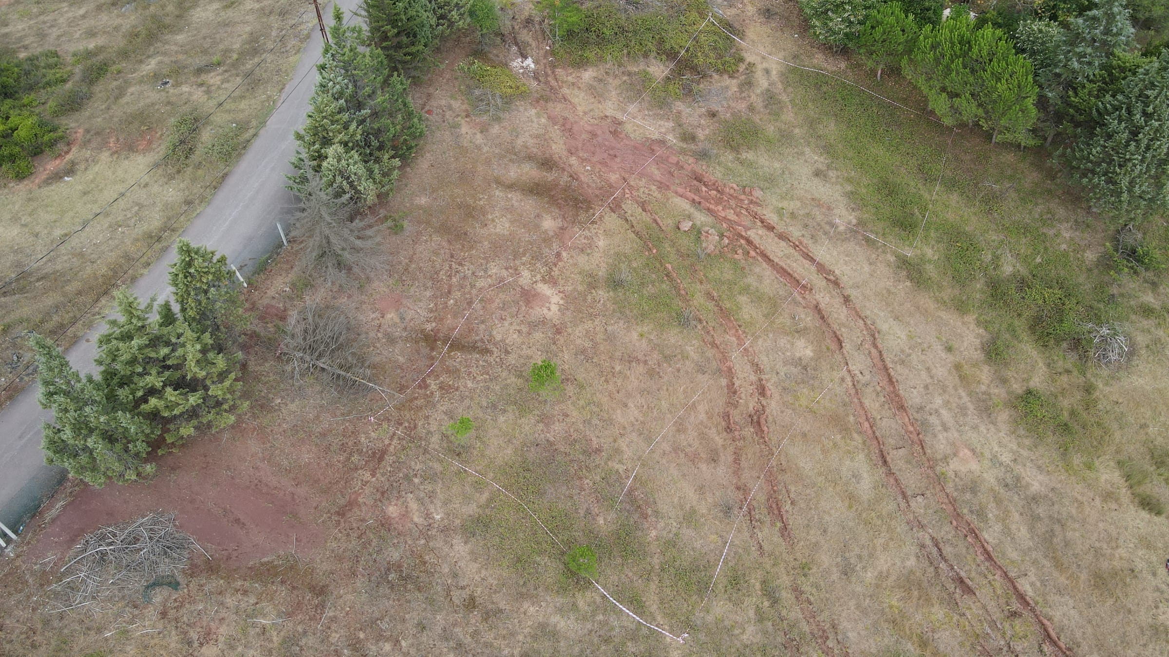 Aerial view of bare ground with marking tapes laid out where a building will stand.